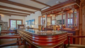 A bar area with wooden furniture, a large mirror, and a stone fireplace.