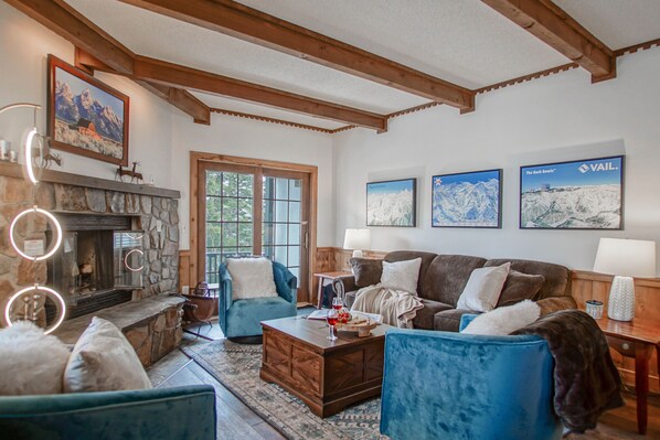 A cozy living room with a stone fireplace, blue armchairs, a wooden coffee table, and framed pictures on the wall. - Whistlepunk #11: 2 Bedroom, 2 Bath: Wood fireplace.Central Location. (Snowshoe)