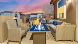 Un patio al aire libre con mobiliario de mimbre, una chimenea y vistas a casas vecinas.