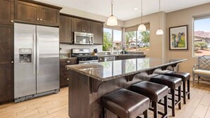 Una cocina moderna con un refrigerador de acero inoxidable, un microondas y una isla grande con taburetes de bar.