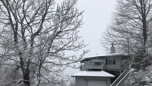 A two-story building with a garage, surrounded by snow-covered trees and a snowy landscape. - Marvelous Panoramic Mountain Views All Year, Private,Club,Skiing Slopes nearby! (Beech Mountain)