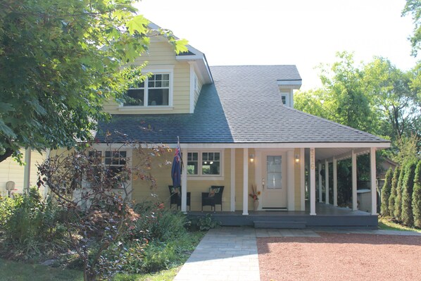 A two-story house with a covered porch, a flag, and a well-maintained garden.