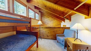 Une chambre dans un chalet en bois, avec des lits superposés, un bureau et une chaise.