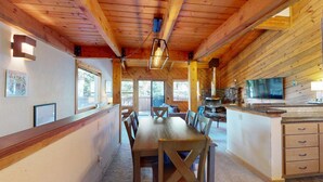 Un intérieur en bois comprenant une table à manger, des chaises, un coin cuisine et une cheminée en pierre.