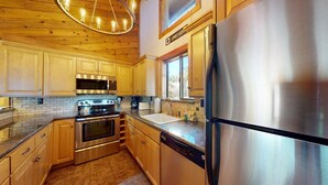Une cuisine avec des armoires en bois, des appareils électroménagers en acier inoxydable et un mur de fond en briques.