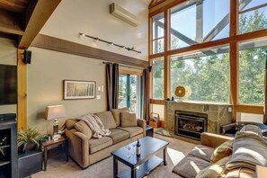 A cozy living room with a fireplace, large windows, and a comfortable sofa. - Greystone Lodge 317 Ski-in/Out by Acer Vacations (Whistler)