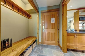 Una panca di legno, una porta e un angolo cottura con pensili e un piano di lavoro.