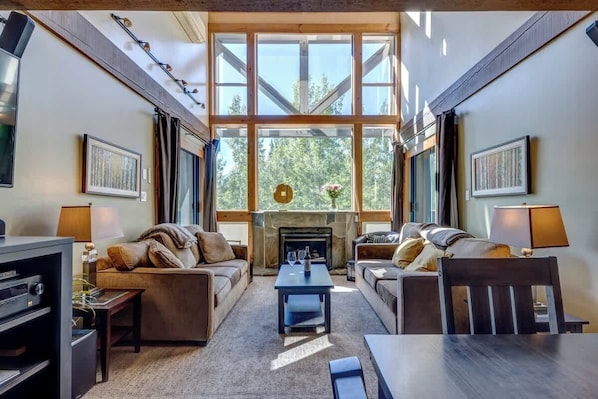 A spacious living room with a fireplace, large windows, and a cozy seating area.