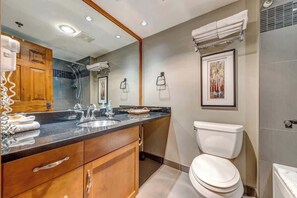 Un bagno moderno con un mobile bagno in legno, uno specchio grande, un water e uno spazio doccia.