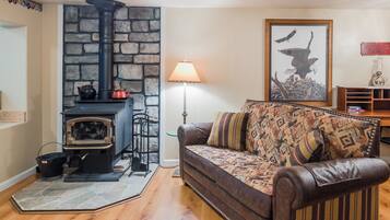 A cozy living room with a stone fireplace, a leather sofa, and a framed picture of an eagle.