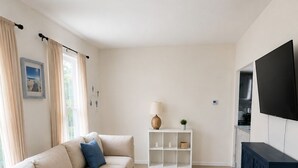 A living room with a sofa, a small table with a plant, a cabinet, and a TV.