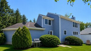 A two-story blue house with a well-maintained lawn, a satellite dish, and a grill.