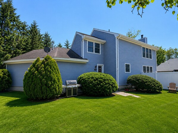 A two-story blue house with a well-maintained lawn, a satellite dish, and a grill. - Bay Head - Open Concept Home with Water View (Point Pleasant)