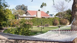 Un hamac dans un jardin, avec un bâtiment en arrière-plan.