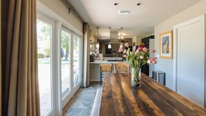 Une cuisine avec une table en bois, un vase de fleurs et un coin repas avec un banc.