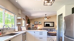 Une cuisine moderne dotée d’une cuisinière intégrée, d’une grande fenêtre et d’un coin repas avec un canapé et un téléviseur.