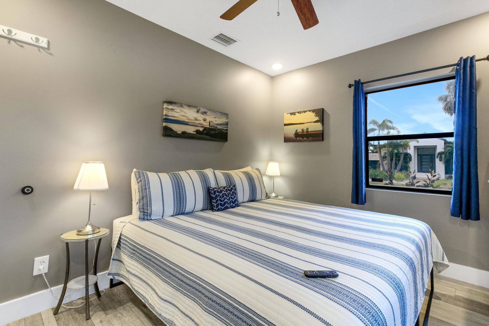 Una camera da letto con un letto, due lampade da comodino, una ventola a soffitto e due quadri alle pareti.