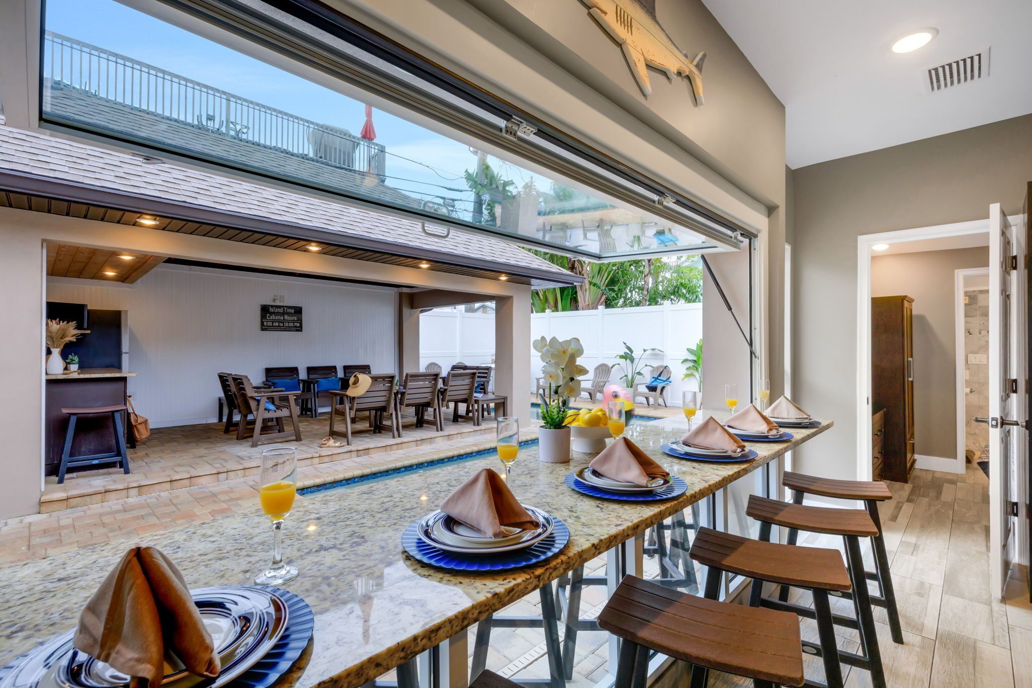 A dining area with a pool view, a bar, and a kitchen area.