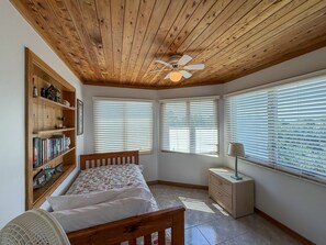 A bedroom with a wooden ceiling, a bed, a nightstand, a lamp, and a bookshelf. - Pirate's Quay 3 South:  Incredible harbor views and sunsets. Docking. (Ocracoke)