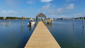 Un muelle de madera que lleva a un pabellón con un bote amarrado al final.