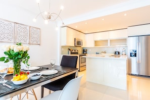 A modern kitchen with white cabinets, stainless steel appliances, and a central island.