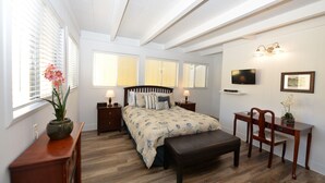 A bedroom with a bed, bedside tables, a desk, a chair, and a TV.
