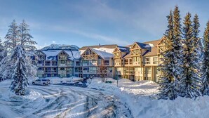 Un hotel de diverses plantes amb un paisatge cobert de neu, incloent arbres i muntanyes al fons.