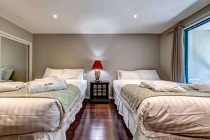 A hotel room with two beds, a nightstand with a lamp, a large window, and a mirror on the wall. - Greystone Lodge 216 Ski-in/Out by Acer Vacations (Whistler)