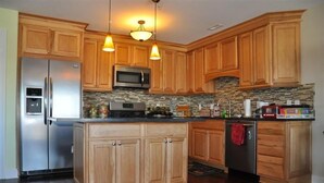 Una cucina con mobili in legno, un frigorifero in acciaio inossidabile, un forno a microonde e una lavastoviglie.