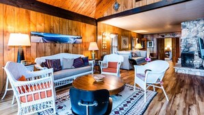 Un salon chaleureux, décoré avec du bois, comprenant un canapé, des fauteuils et une cheminée.