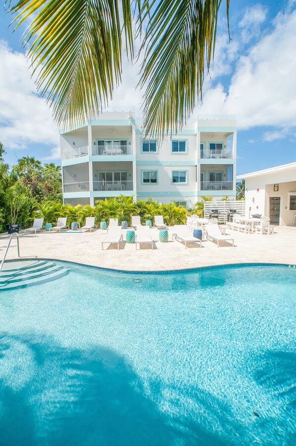 A pool area with lounge chairs and a building in the background.