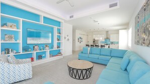 A modern living room with a blue sofa, a round coffee table, and a TV mounted on the wall.