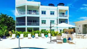 A modern hotel with a pool, multiple balconies, and outdoor seating areas.