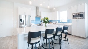 A modern kitchen with white cabinets, stainless steel appliances, and a central island with bar stools.