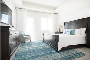 A bedroom with a dark wood bed, a white dresser, a gray armchair, and a blue rug.