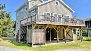 A two-story house with a wooden deck and a covered porch. - Stranded On Purpose "Bluebird Day Too":  Spacious dog friendly with a pool table (Ocracoke)