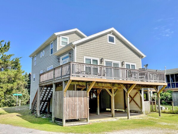 A two-story house with a wooden deck and a covered porch. - Stranded On Purpose "Bluebird Day Too":  Spacious dog friendly with a pool table (Ocracoke)