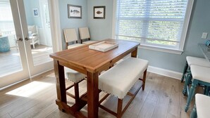 A dining area with a wooden table and benches, framed fish pictures on the wall, and a window with blinds. - Stranded On Purpose "Bluebird Day Too":  Spacious dog friendly with a pool table (Ocracoke)