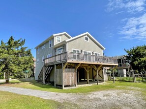 A two-story house with a wooden deck and a covered porch. - Stranded On Purpose "Bluebird Day Too":  Spacious dog friendly with a pool table (Ocracoke)