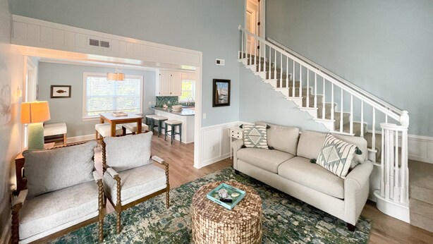 A spacious living room with a sofa, armchairs, a coffee table, and a staircase. - Stranded On Purpose "Bluebird Day Too":  Spacious dog friendly with a pool table (Ocracoke)
