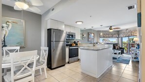 Una cocina moderna con armarios blancos, electrodomésticos de acero inoxidable y una isla central.