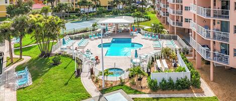 A resort with a central pool, outdoor seating, and a well-maintained lawn.