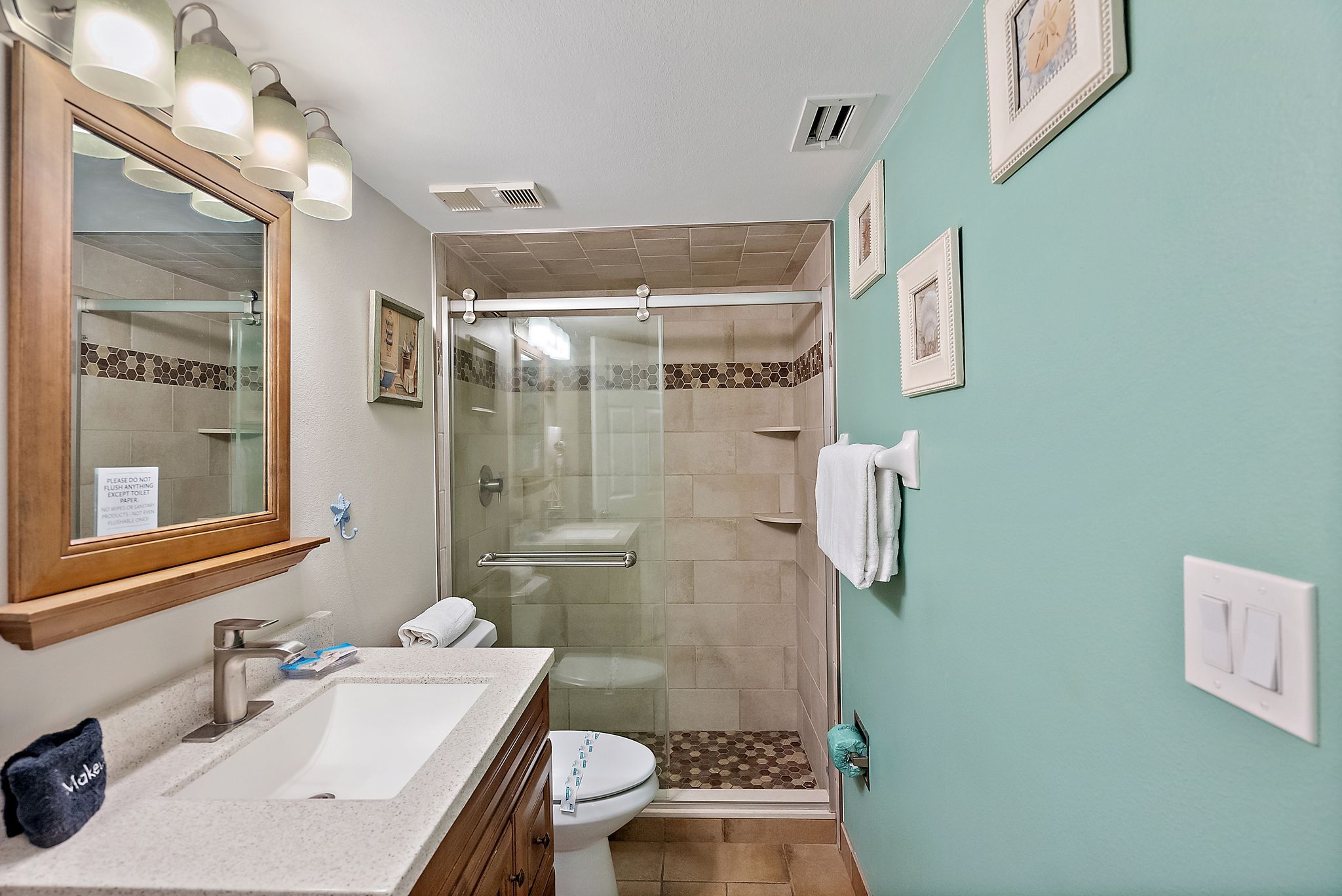Un bagno con lavandino, specchio, doccia e WC.