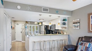 Una cocina moderna con una isla central, taburetes de bar y una zona de estar con un sofá de cuero.