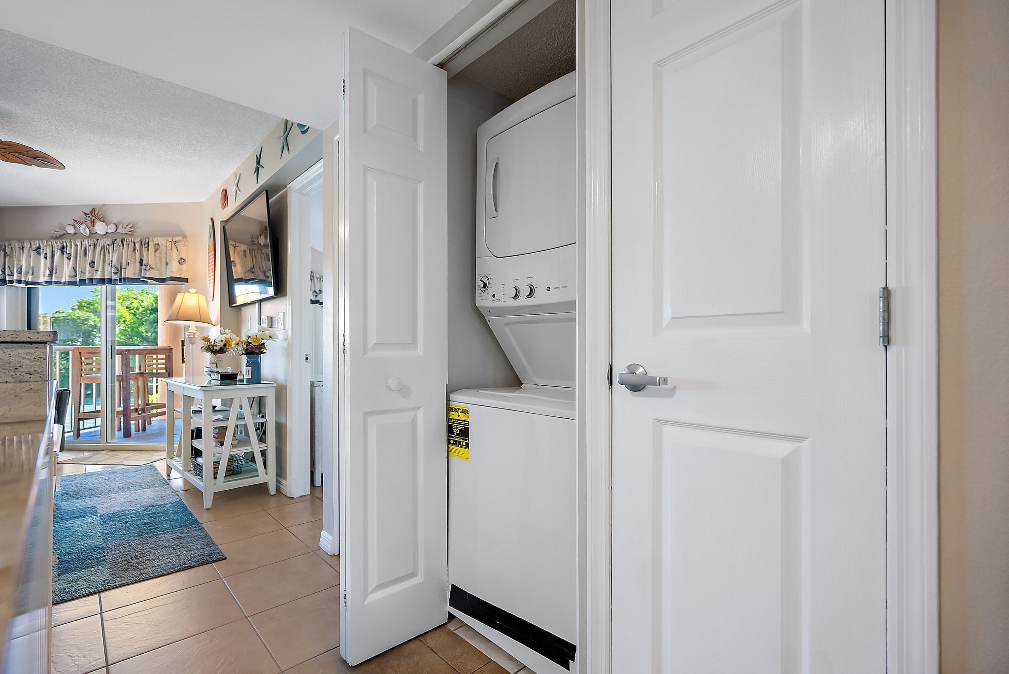 A laundry room with a washer and dryer, a small table with a lamp, and a door leading to another room.