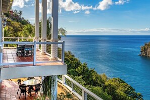 Enjoy the ocean view from this terrace with a table and chairs.