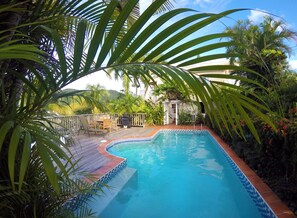 Relax by the serene pool surrounded by lush tropical vegetation and a shaded gazebo.