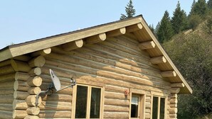 Une cabane en rondins avec un jacuzzi, une antenne parabolique et une petite fenêtre.