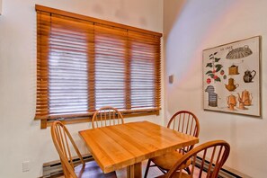 Enjoy meals in this dining area with a table and chairs, adjacent to a window with blinds.