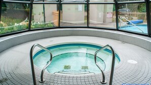 Une piscine intérieure avec un sol carrelé et des échelles métalliques.